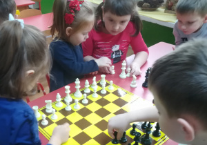 Dzieci ustawiają figury szachowe na szachownicy